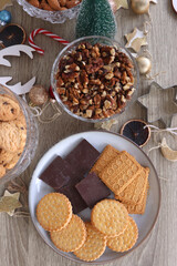 Various Christmas decorations, cookies, chocolate and nuts on wooden background. Flat lay.