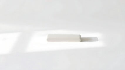 Minimalist white rectangular object on pure white surface, showcasing clean modern design.