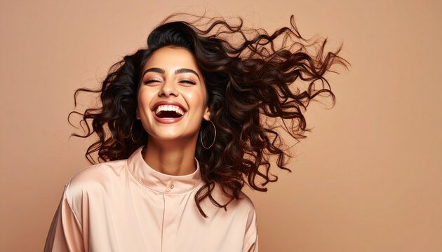 Joyful young woman with beautiful voluminous curly hair laughs happily, her dark tresses flying freely and vibrantly.