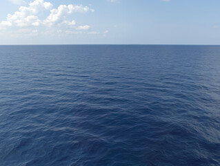 Obraz premium Vast ocean view showcases deep blue waters under clear sky with scattered clouds, evoking sense of tranquility and openness. serene atmosphere invites reflection and appreciation of nature beauty