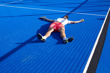 Tired man lying on the padel court after the game
