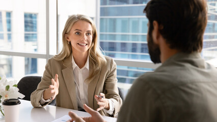 Fototapeta premium Happy blonde young businesswoman talking to business partner