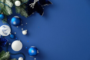 Elegant Christmas flat lay with snowy pine branches, velvet poinsettia, and blue ornaments on a...