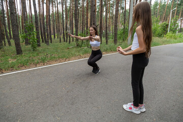 Mother and child daughter are engaged in running and athletics in the summer in the forest