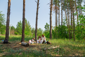 Grandmother and granddaughter resting in log after riding skateboard in the forest in summer