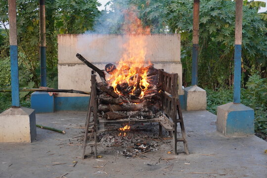 Hindu outdoor funeral pyre burning on wooden bier at rural cremation ground in India