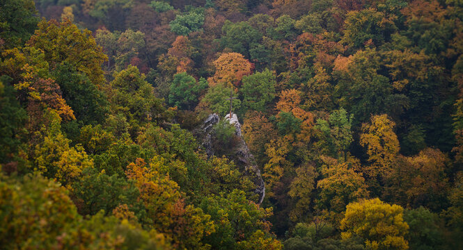 The wooden cross of Moln&aacute;r Rock surrounded by colorful autumn forest, viewed from the Szeleta Cave trail in the B&uuml;kk Mountains, Hungary. Peaceful and moody scene.