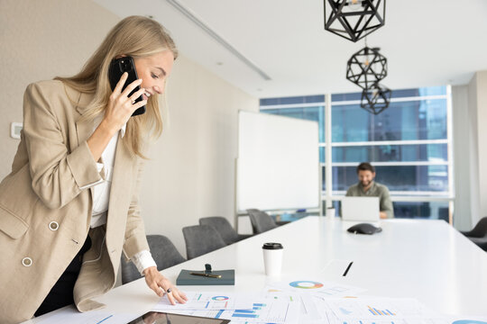 Positive busy analyst woman talking on mobile phone