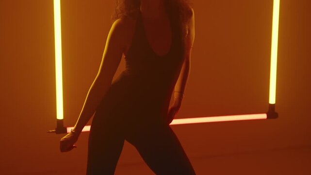 Dynamic close up of the dancer silhouette dancing against the glowing orange neon square - Powered by Adobe