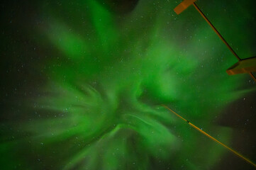 A mesmerizing display of green aurora lights fills the night sky, creating a mesmerizing, swirling pattern against the dark backdrop