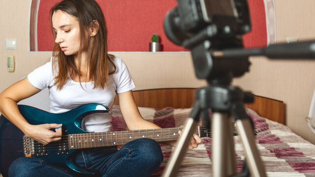 Young woman having online guitar class at home