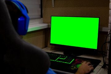 Person sits at gaming desk with green screen displayed on monitor. The setup invites creative integration, allowing users to place their own projects in gaming environment
