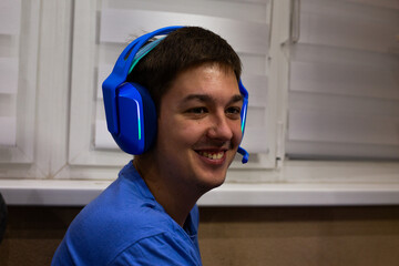 Gamer immersed in moment of joy, wearing vibrant blue headphones, enjoying their gaming experience with authentic emotions. Connection to game and emotions of excitement and fun are evident