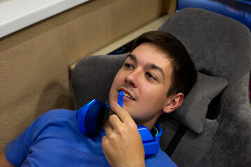 Young gamer having removed his headphones, uses microphone to chat with friends online, creating social and interactive gaming experience through the internet