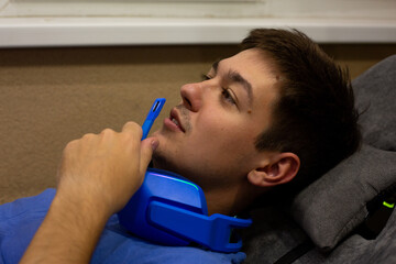 Young gamer relaxed on couch, holding microphone close to his mouth, chatting with friends during break between gaming sessions. The image captures laid back, social gaming moment