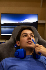 Gamer enjoys relaxing moment between sessions, casually chatting with friends over microphone. Peaceful setting, with scenic view on the screen, reflects the balance of gaming and downtime