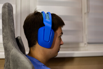 Focused gamer immersed in his gaming experience, wearing stylish blue headphones. Intensity and concentration of gaming process, perfect for tech and gaming related content