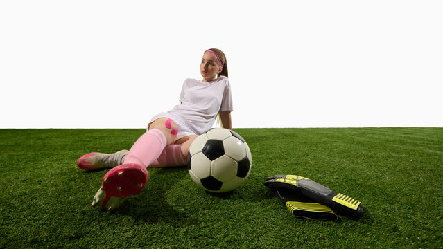 Female football player resting on field with ball and gloves showing calm recovery. Concept of sportswear branding, health recovery, editorial sports storytelling, and motivation in media. - Powered by Adobe