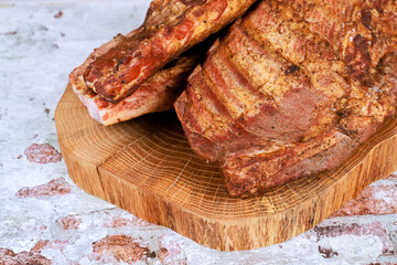Smoked pork ribs coated with spices sit on wooden board evoking sense of culinary preparation.