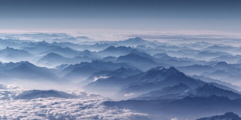 Fototapeta premium Layers of blue mountain ranges and peaks emerging through a serene fog from an aerial view
