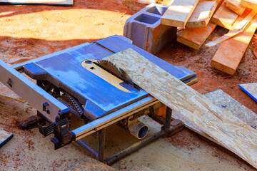 Circular saw is cutting through piece of plywood at busy construction site surrounded by wooden materials.