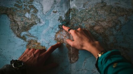 Traveller hands pointing on a vintage paper map by soft window light, planning the next adventure; evocative storytelling for tourism, road trips, exploration, and inspirational travel content