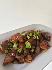 Ayam kecap, chicken with soysauce on white plating upper side view