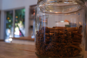 Closeup image of bundle of curved, rolled brown cinnamon sticks filled in a glass jar.