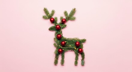 Festive reindeer flat lay made of evergreen fir and red baubles — minimal Christmas decoration on pastel pink background