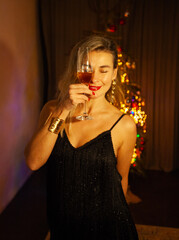 Woman toasting with champagne by a Christmas tree on New Year&rsquo;s Eve