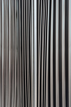 An abstract, close-up shot of the vertical folds and pleats of the accordion joint on an articulated bus, showing a pattern of light and shadow
