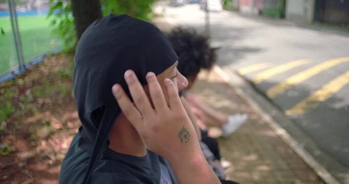 African American man tying durag on head near street and sports field, expressing confidence, cultural pride, and everyday urban style in casual outdoor environment