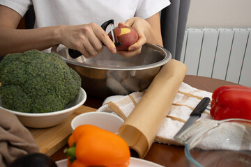 A woman peels potatoes. Healthy eating, Cooking. Vegetables on the table.