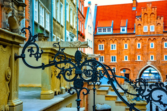 Captivating view of intricate wrought iron railings set against the historic red brick buildings in Gdansk Old Town. The architectural detail reflects the city's rich history