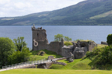Urquhart Castle by a lake with mountains in the background. Loch Ness