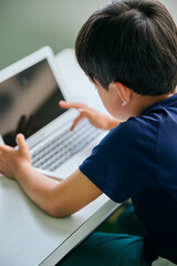 ノートパソコンでオンライン学習をする小学生の男の子