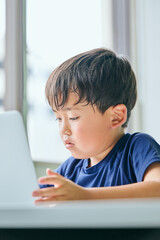 ノートパソコンでオンライン学習をする小学生の男の子
