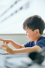 ノートパソコンでオンライン学習をする小学生の男の子