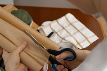 A woman cutting baking paper with scissors. Cooking. Vegetables on the table. Healthy eating.