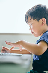 ノートパソコンでオンライン学習をする小学生の男の子
