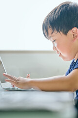 ノートパソコンでオンライン学習をする小学生の男の子