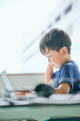 ノートパソコンでオンライン学習をする小学生の男の子