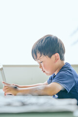 ノートパソコンでオンライン学習をする小学生の男の子