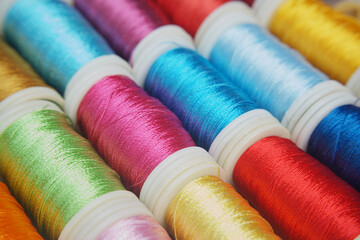 Vibrant thread spools in an artistic macro shot. A collection of colorful thread spools create a visually captivating display, perfect for crafts and creative projects.