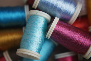 Vibrant, close-up captures a mesmerizing assortment of multicolored thread spools, each thread a different color, reflecting the colorful spectrum.
