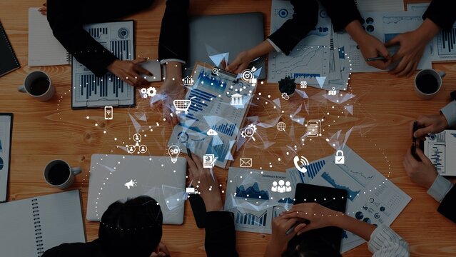 A team engages in a collaborative business meeting, analyzing data and charts in a modern workspace. Digital icons reflect finance and technology themes, enhancing insights. Raster