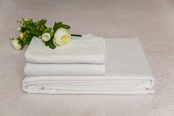 Soft white towels and delicate flowers arranged elegantly on a light textured surface