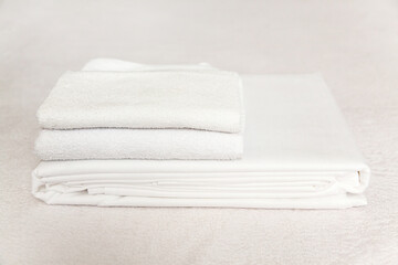 Freshly folded white towels stacked neatly on a soft surface for a clean look