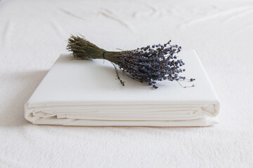 Freshly folded white linens with a lavender bundle on a soft surface © Kathleen