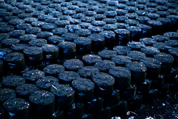 Bundles of Charcoal Stacked Neatly in a Dark Setting for Sale